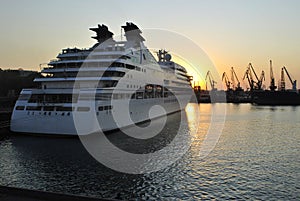 Luxury cruise ship sailing to port on sunrise.
