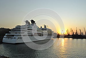 Luxury cruise ship sailing to port on sunrise.