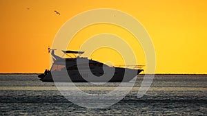 Luxury cruise trip. Red burning sunset over the sea with silhouette of rich yacht. Abstract nature summer ocean sea