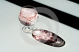 Luxury crystal glass with shampagne and its shade on a white tab