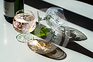 Luxury crystal glasses and a bottle of shampagne lit by harsh li