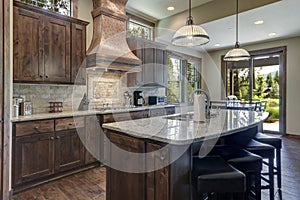 Luxury dark wood rich kitchen interior with copper stove hood and grey natural stone backsplash