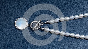 Luxury elegant baroque pearl necklace with pendant on dark blue textured leather background