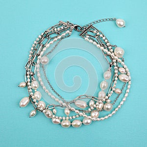 Luxury elegant baroque pearl and silver bracelet on bright turquoise textured background