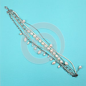Luxury elegant baroque pearl and silver bracelet on bright turquoise textured background