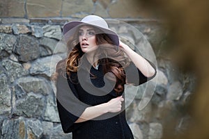 Luxury elegant woman in trendy black coat and hat standinf near