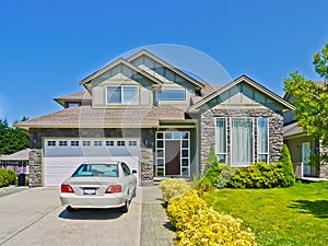 Luxury family house with luxury car parked on concrete driveway on sunny day