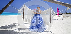 Luxury fashion. Elegant fashion model. Stylish female model in elegant long gown dress on the Maldives beach. Elegance. Bride on