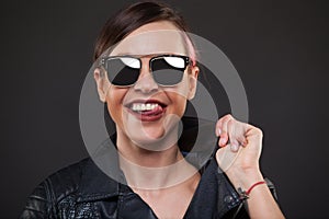Luxury Fashion model, a beautiful woman posing in studio on gray background with glasses from the sun. Smile, licks his
