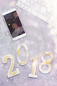 Luxury glowing numbers 2018 with cell phone and keyboard under snow on grey background
