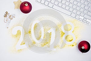 Luxury glowing numbers 2018 made from gold shiny glitter on white table with keyboard and christmas decoration