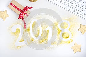 Luxury glowing numbers 2018 made from gold shiny glitter on white table with keyboard and christmas decoration