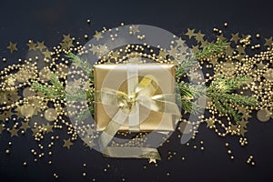 Luxury golden gift box with gold ribbon on shine black background. Christmas present. Flat lay. Top view. Xmas