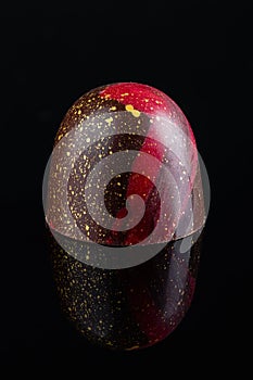 Luxury handmade bonbon decorated with gold and red paint on black background