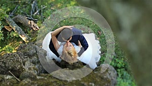 Luxury happy blonde bride and stylish groom tenderly kiss in the green summer forest, tender moment. Top view