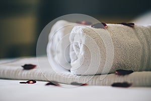 Luxury hotel room with white spa towels on bed sheet with rose petals. Romantic holiday weekend with wellness body treatment  and