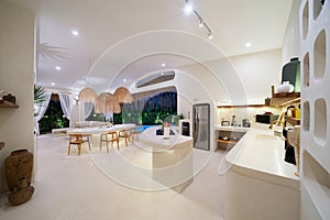 Luxury interior design in living room with open space kitchen. Airy and bright space with high raised ceiling and stone