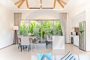 Luxury interior design in living room of pool villas. Airy and bright space with high raised ceiling and kitchen area with dining