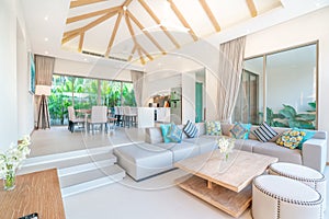 Luxury interior design in living room of pool villas. Airy and bright space with high raised ceiling, sofa, middle table, dining