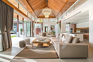 Luxury interior design in living room of pool villas. Airy and bright space with high raised ceiling and wooden dining table photo