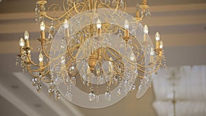 Luxury large crystal chandelier hanging. Vintage lighting lamps with light bulbs and a lot of pendants.