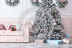 Luxury living room interior with sofa decorated chic Christmas tree, gifts and pillows. Classic interior in pink shades. Christmas