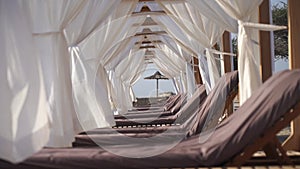 Luxury lounge with sun chair and white curtains on the beach. Vacation and relaxation concept