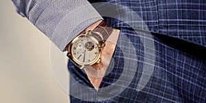 Luxury male wrist watch worn on arm in trousers pocket, time