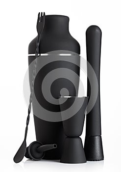 Luxury matte black coloured cocktail set with shaker and muddler and measuring jigger with spoon on white