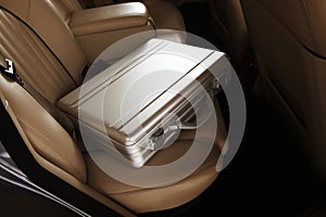 Luxury metal briefcase on a vinage car back seat. Creme leather