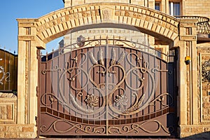 Luxury metal wrought iron gates and a stone arch for the entrance to a private house