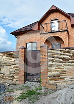 Luxury modern brick house under construction with stone fence and metal entrance door