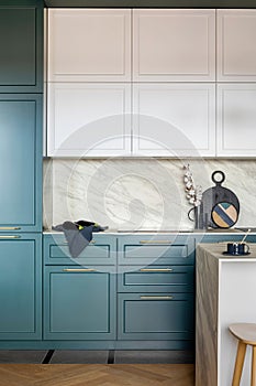 Luxury modern and vintage turquoise and white kitchen. Marble wall with white cabinets. Black vase with white dried flowers.