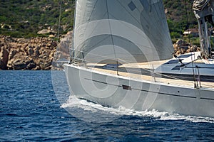 Luxury new cruising sailboat bow with teak deck under hoisted sails.