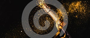 Luxury new year background. Champagne bottle with gold ribbon on dark background with golden bokeh glitter firework. Christmas