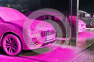 Luxury orange car on self servise car washing. Pink foam on auto