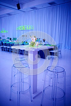 Luxury orchid cocktail flower arrangement on lucite stools and table set up for a party in a ballroom