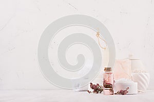 Luxury organic body and skin care spa cosmetics collection, pink oil, flowers, natural bath accessories on white wood background.