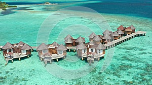 Luxury overwater villas from above on tropical sea. Aerial drone view.