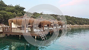 Luxury overwater villas with palm trees, blue lagoon. Beach travel vacation. Typical overwater bungalows with straw