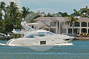 Luxury powerboat cruising tropical canal and condominiums