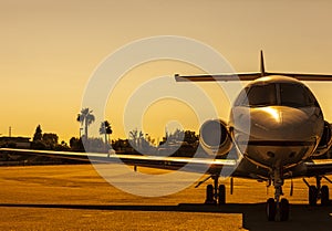 Luxury private jet is parked on an airfield during gorgeous golden sunset