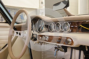 Luxury Race Retro Car Interior With Beige Finish. Speedometer And Tachometer On Dashboard. Car In Workshop