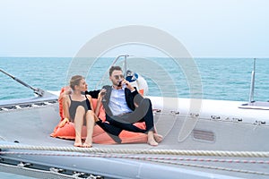 Luxury relaxing couple traveler in nice dress and suite sit on bean bag and drink a glass of wine in part of cruise yacht with