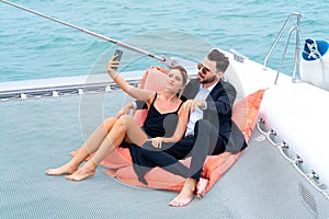 Luxury relaxing couple traveler in nice dress and suite sit on bean bag and drink a glass of wine in part of cruise yacht with