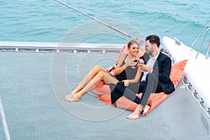 Luxury relaxing couple traveler in nice dress and suite sit on bean bag and drink a glass of wine in part of cruise yacht with