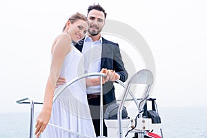 Luxury relaxing couple traveler in nice dress and suite stand with driver hand steering wheel on boat yacht. Concept business