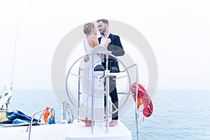 Luxury relaxing couple traveler in nice dress and suite stand with driver hand steering wheel on boat yacht. Concept business