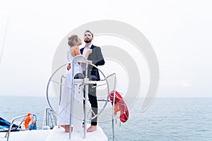 Luxury relaxing couple traveler in nice dress and suite stand with driver hand steering wheel on boat yacht. Concept business