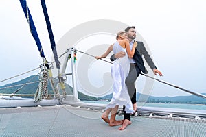 Luxury relaxing couple traveler in nice dress and suite stand at part of cruise yacht with background of water sea and white sky.